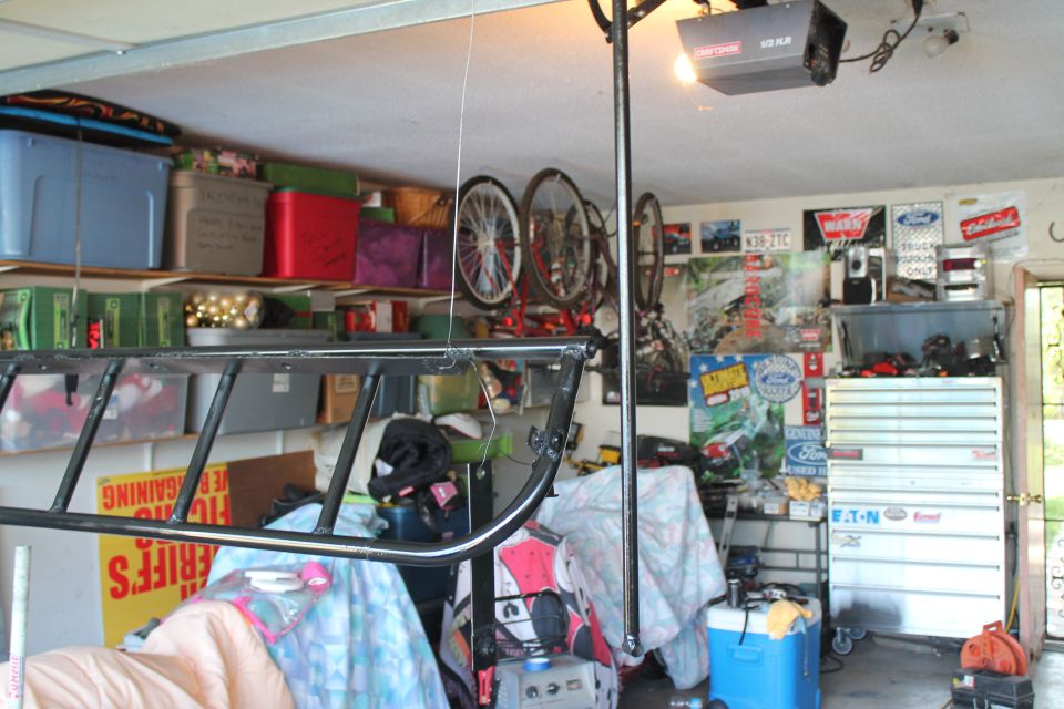 Garage interior with shelves full of bins, bicycles hanging, tool chest, and posters on the wall