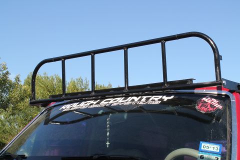 1990 Ford Bronco - A black metal roof rack is attached to the top of a red vehicle.