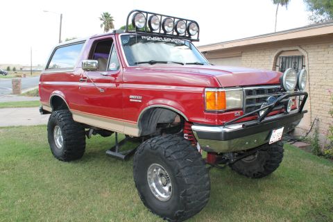 1990 Ford Bronco - This red 1990 Ford Bronco features a lifted suspension and a roof-mounted light bar.