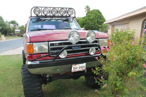 1990 Ford Bronco - This red Ford Bronco features a light bar and auxiliary lights, with a license plate reading DH4-8404.