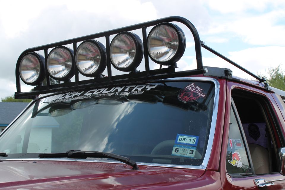 Red SUV with roof-mounted light bar and 'Rough Country' sticker