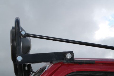 1990 Ford Bronco - Close-up view of a black light bar and headlight mounted on the roof of a red SUV.
