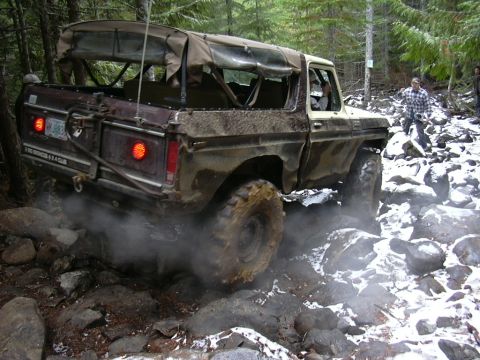 1991 Ford Bronco - Ford Bronco tackling a challenging rocky off-road path in a wooded area.