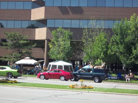 1970 Ford Ranchero - A gathering of people are seen near tents and vehicles in front of a modern office building.