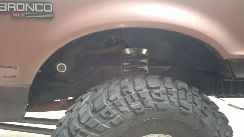 1992 Ford Bronco - Close-up view of the fender well and tire of a 1992 Ford Bronco XLT, highlighting suspension modifications.