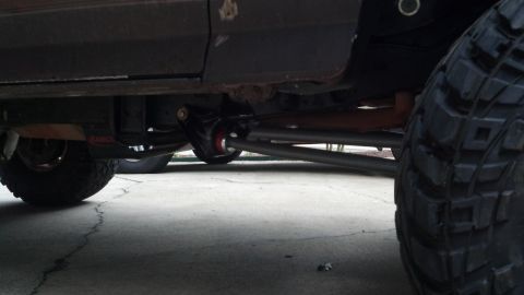 1992 Ford Bronco - Close-up of the undercarriage and suspension system of a vehicle, with a prominent tire in the foreground.