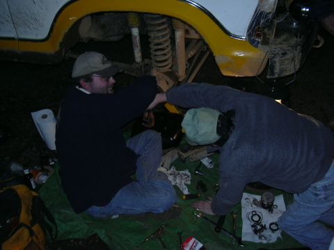 1991 Ford Bronco - Two men work on the suspension of a 1991 Ford Bronco, possibly during an off-road trip.
