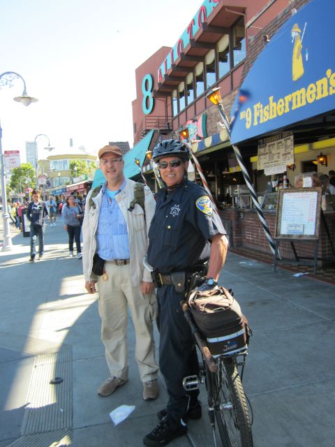 1991 Ford LTD Crown Victoria - Two men pose for a photo on a busy street, with a police officer and his bicycle in the foreground.