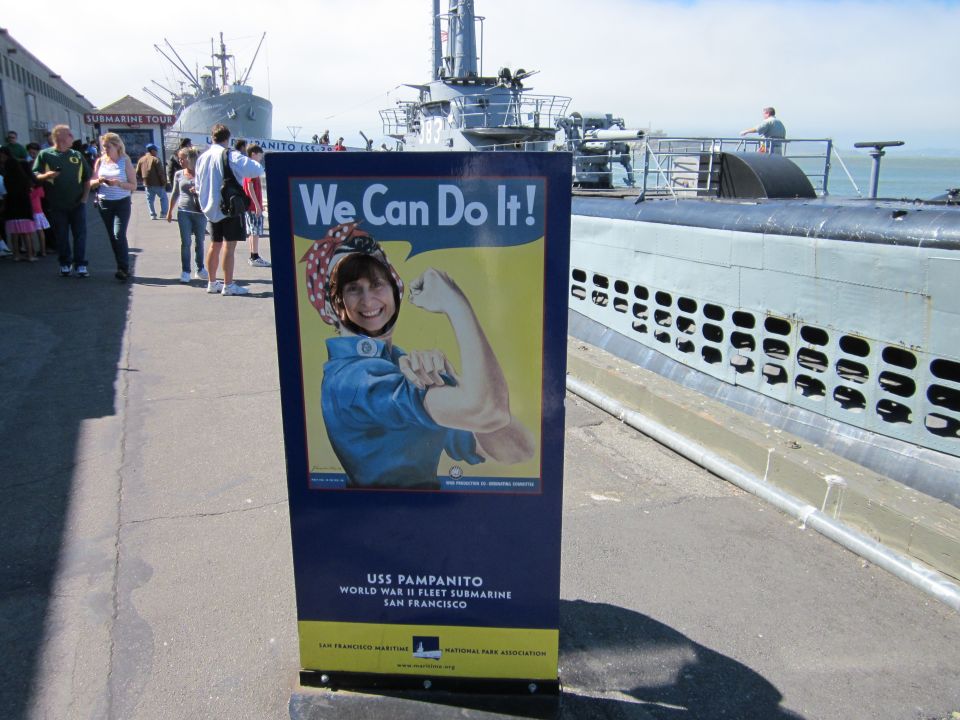 Sign for USS Pampanito submarine with 'We Can Do It!' graphic, next to a submarine