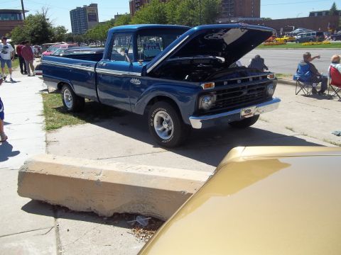 1970 Ford Ranchero - This blue Ford F-Series pickup truck, likely from 1965, is displayed with its hood open, revealing the engine bay.