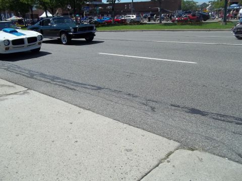 1970 Ford Ranchero - A white car with a blue hood scoop is parked next to a green 1967 Ford Mustang on a sunny day.