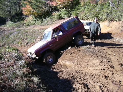 1991 Ford Bronco - A Ford Bronco navigates a challenging muddy terrain during an off-road excursion.