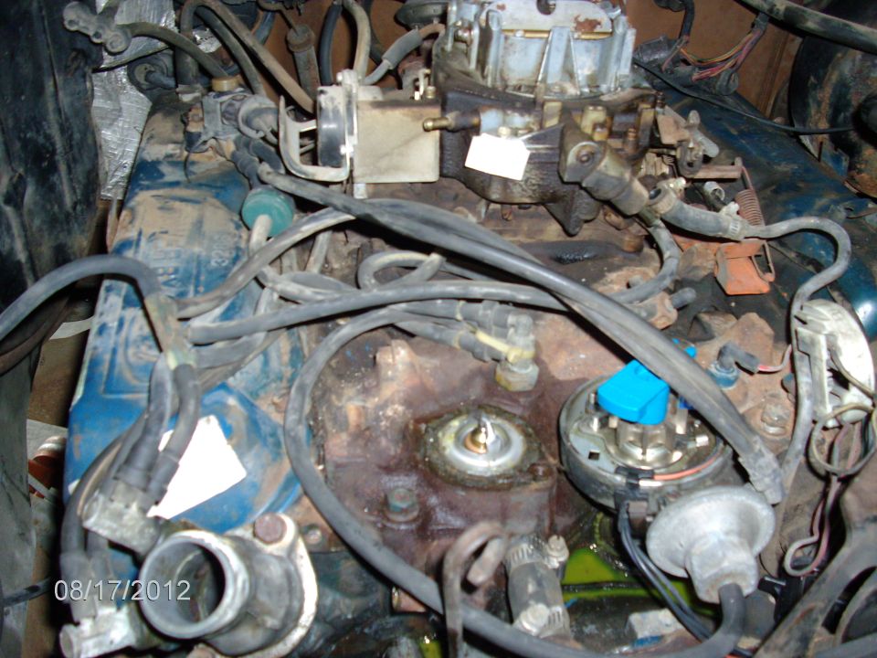 Close-up of an engine bay, showing the carburetor, distributor, and various hoses. Date stamp '08/17/2012' visible