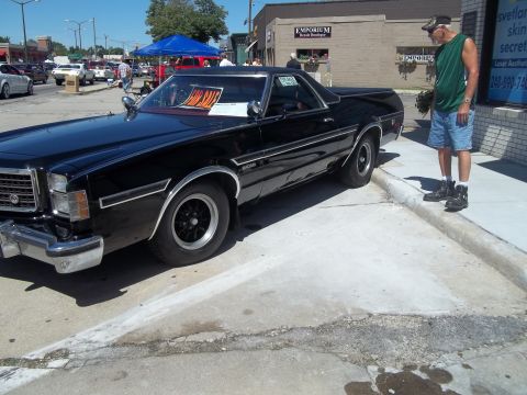 1970 Ford Ranchero - A black 1970 Ford Ranchero is parked on a street with a man standing nearby and an orange 'For Sale' sign visible in the window.
