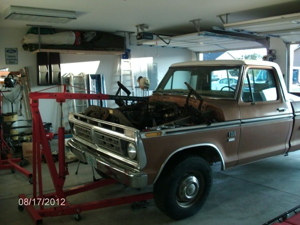 1979 Ford F-150 truck in garage with engine hoist next to it, hood open, engine removed