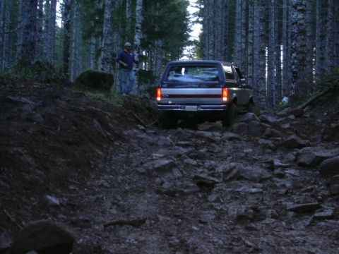 1991 Ford Bronco - A 1991 Ford Bronco navigates a challenging, rocky path through a dense forest.