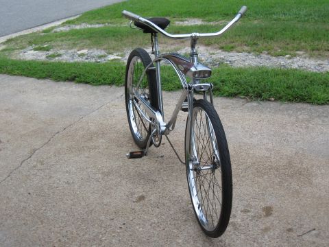1994 Ford Bronco - A shiny chrome cruiser bicycle with a distinctive headlight is parked on a concrete path.