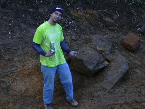 1991 Ford Bronco - A man stands on a dirt embankment, holding a beverage and gesturing towards large rocks.