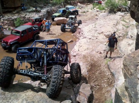 1966 Ford Bronco - Several off-road vehicles traverse a water-filled rocky canyon trail.