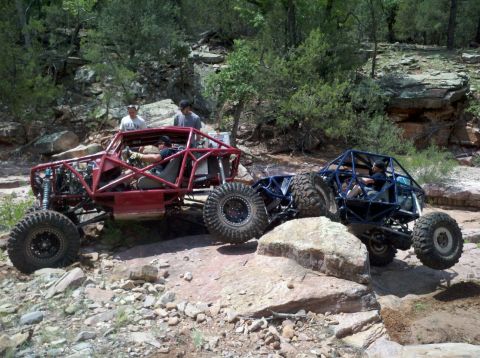 1966 Ford Bronco - Two custom off-road buggies tackle a challenging rocky trail in a natural landscape.