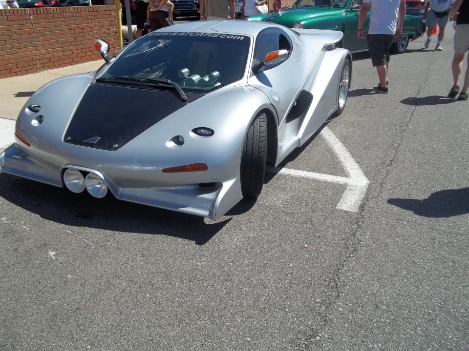 Silver custom sports car with black hood, dual headlights, and aggressive body kit