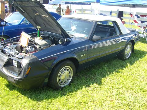 2007 Ford Mustang - A dark blue convertible is displayed with its hood open, revealing the engine and a trophy.
