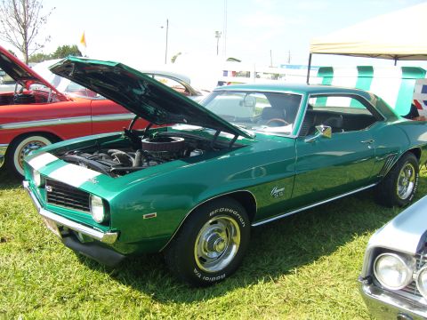 2007 Ford Mustang - A green 1969 Chevrolet Camaro SS is displayed with its hood open at an outdoor car show.