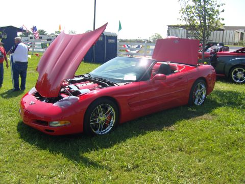 2007 Ford Mustang - A red convertible sports car is displayed with its hood open at an outdoor event.