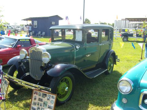 2007 Ford Mustang - A vintage green sedan is displayed at an outdoor event, with other vehicles visible in the background.
