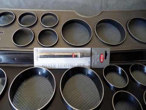 1994 Jeep Cherokee - Gauge bezels and a silver leafing pen are laid out on a textured surface.