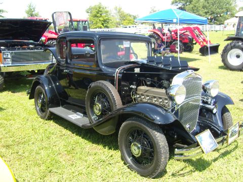 2007 Ford Mustang - A vintage black coupe is displayed outdoors with tractors visible in the background.