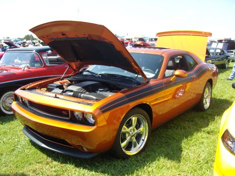 2007 Ford Mustang - Orange Dodge Challenger with black stripes, hood and trunk open, at a car show.