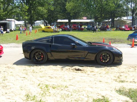 2007 Ford Mustang - A black Chevrolet Corvette with red racing stripes is parked at an outdoor event.