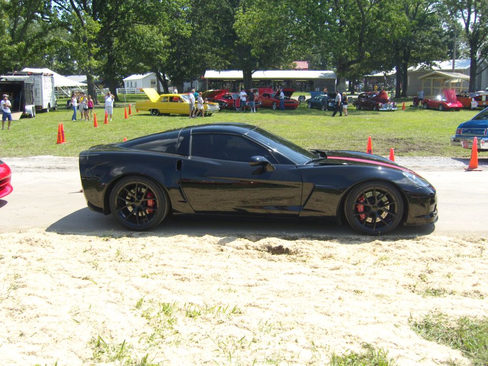 Black Chevrolet Corvette with red racing stripes on the hood, side view