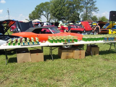 2007 Ford Mustang - An orange convertible is displayed at a car show, surrounded by numerous trophies on tables.