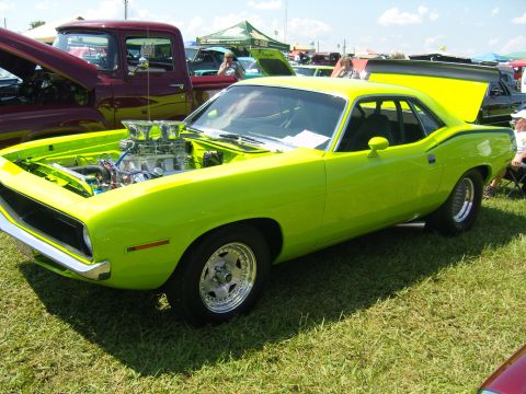 2007 Ford Mustang - A lime green 1970 Plymouth Barracuda is displayed at an outdoor car show with its hood open.