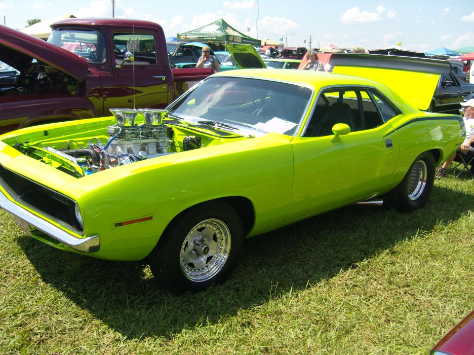 Lime green 1970 Plymouth Barracuda with a large V8 engine exposed under the hood, chrome trim, and racing stripes