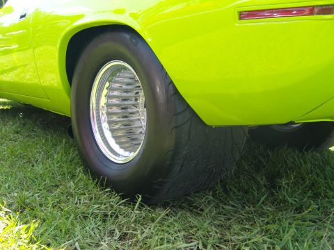 2007 Ford Mustang - Close-up of a bright green muscle car's rear tire and fender, parked on grass.