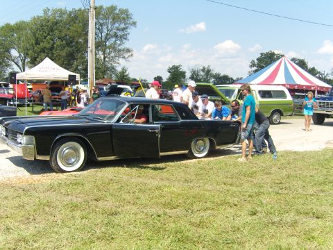 2007 Ford Mustang - A black classic car is displayed at a car show with people gathered around.