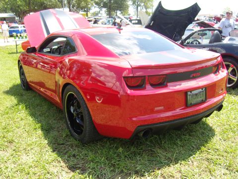 2007 Ford Mustang - A red Chevrolet Camaro RS is parked on grass with its hood open, next to another car.
