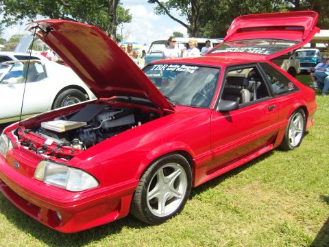 2007 Ford Mustang - A red coupe is displayed with its hood and trunk open at an outdoor event.