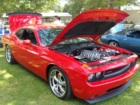2007 Ford Mustang - Red Dodge Challenger on display with its hood and trunk open, revealing the engine and a rear spoiler.