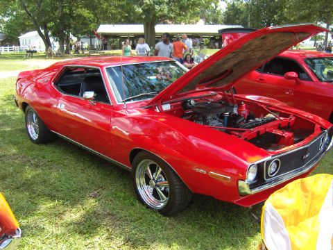 2007 Ford Mustang - A red muscle car is displayed with its hood open at an outdoor event, with another red car visible behind it.