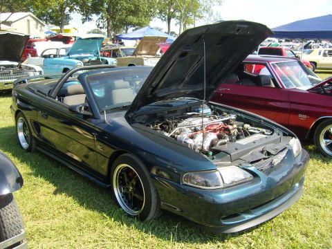 2007 Ford Mustang - A dark green convertible is parked on grass with its hood open, revealing the engine compartment.