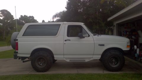 1995 Ford Bronco - A white 1995 Ford Bronco is parked in a driveway next to an open garage.