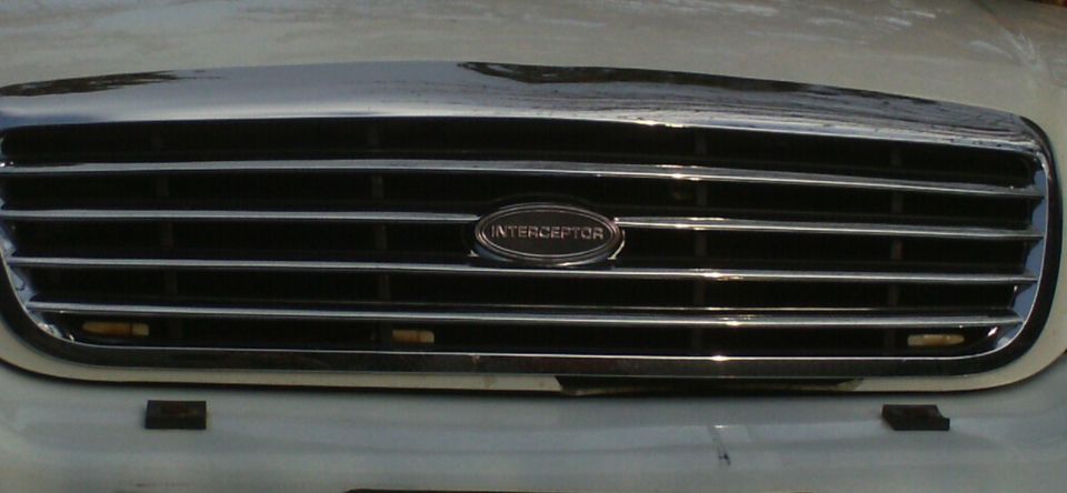 Chrome slatted grille with oval INTERCEPTOR badge on a white Ford Crown Victoria