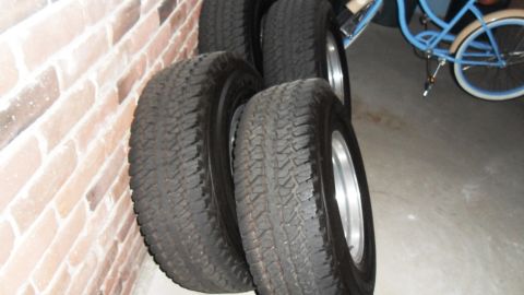 1993 Jeep Cherokee - Set of four tires and wheels leaning against a brick wall with a bicycle in the background.