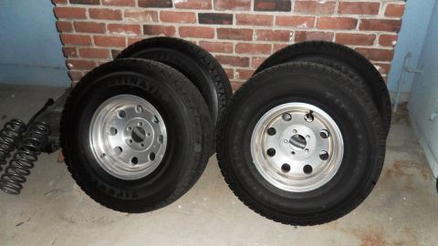 1993 Jeep Cherokee - A set of four tires and wheels are displayed against a brick wall, with other vehicle parts nearby.