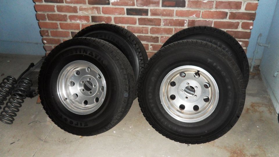four tires on aluminum wheels, plus some suspension springs and a transmission or transfer case in the background