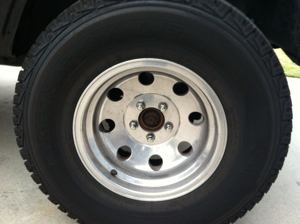 Close-up of a silver multi-hole wheel with a black tire. Supermotors.net logo visible